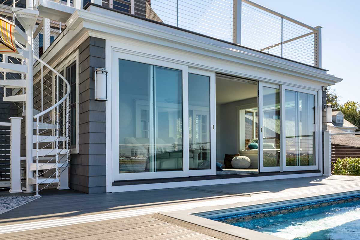 The exterior of a Marvin Modern Multi-Slide door looking into a living room that overlooks a pool and the Logan airport runways.