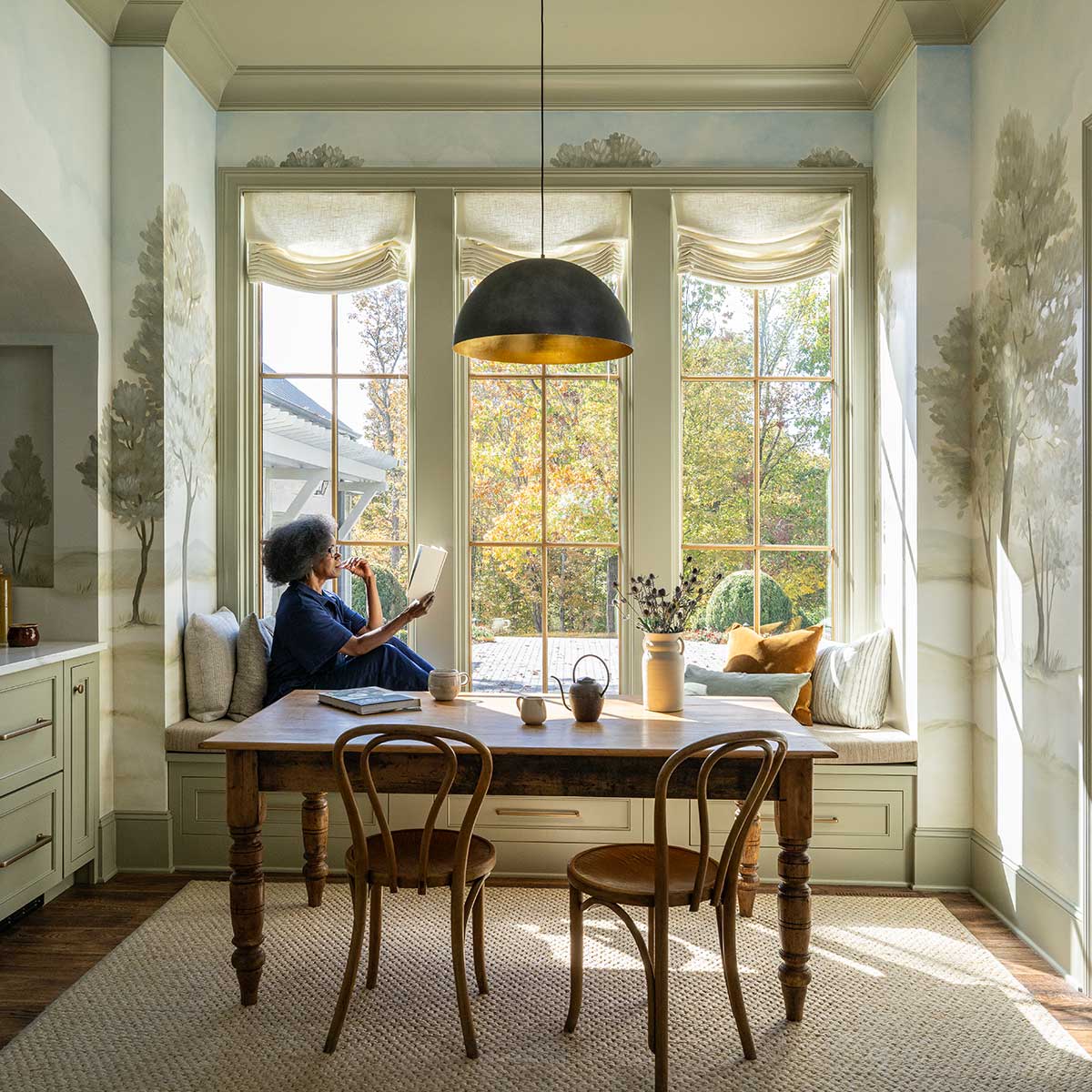 A woman reading a book in a window seat in the 2023 Southern Living Idea House in Nashville, TN.