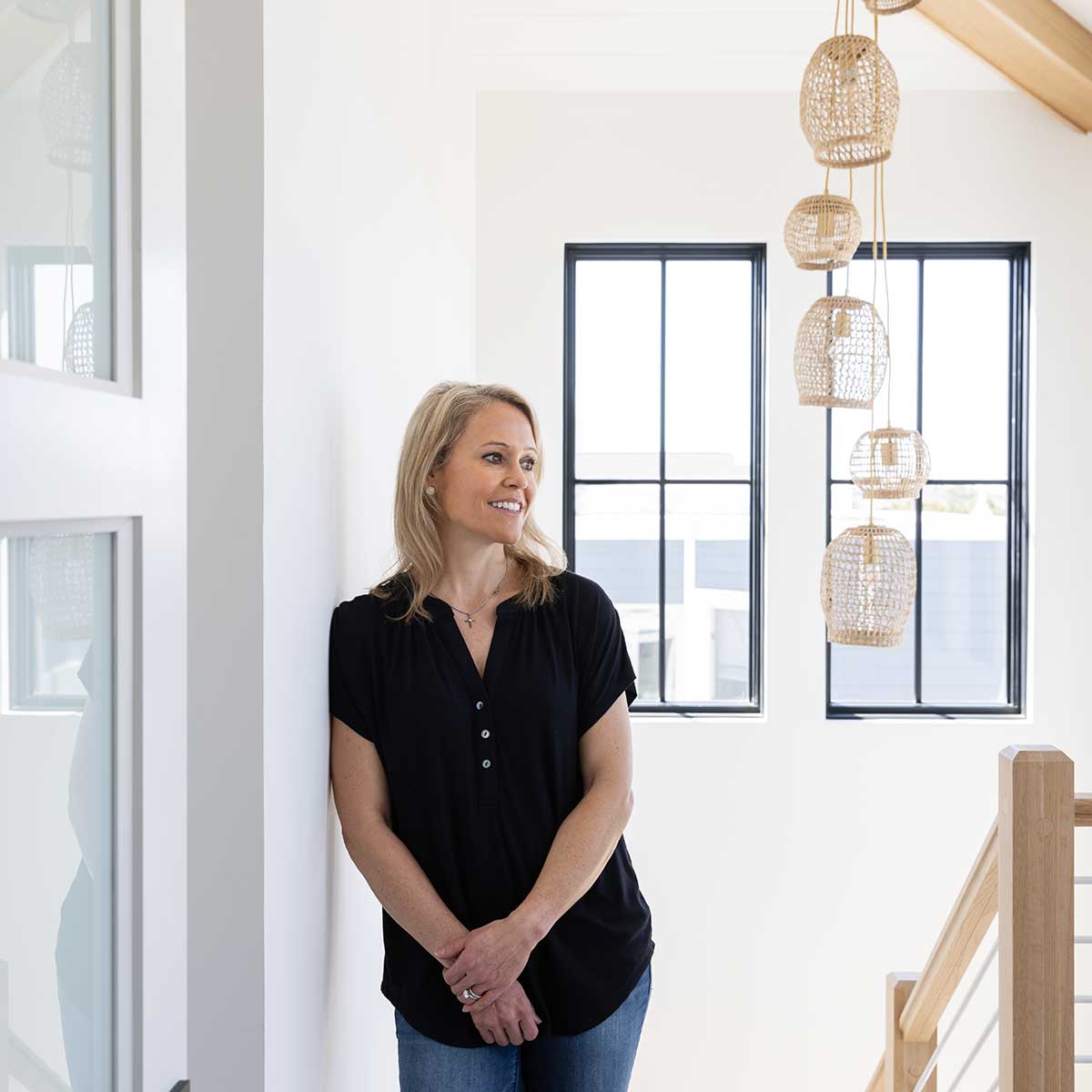 Marnie Oursler, founder and president of Marnie Custom Homes, standing in front of two Marvin Elevate Direct Glaze windows.