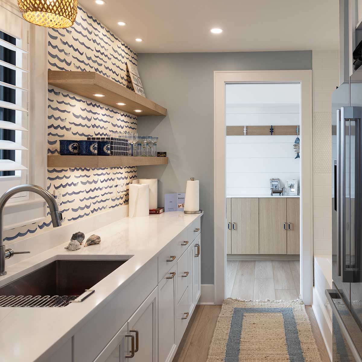 A contemporary laundry room with wave wallpaper, white countertops and lower cabinets and open shelving.
