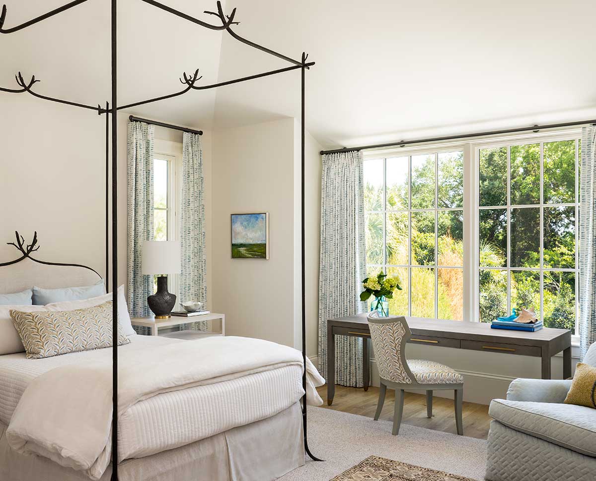 A traditional bedroom featuring a four-poster bed and a desk beneath Marvin Ultimate Casement Picture windows.