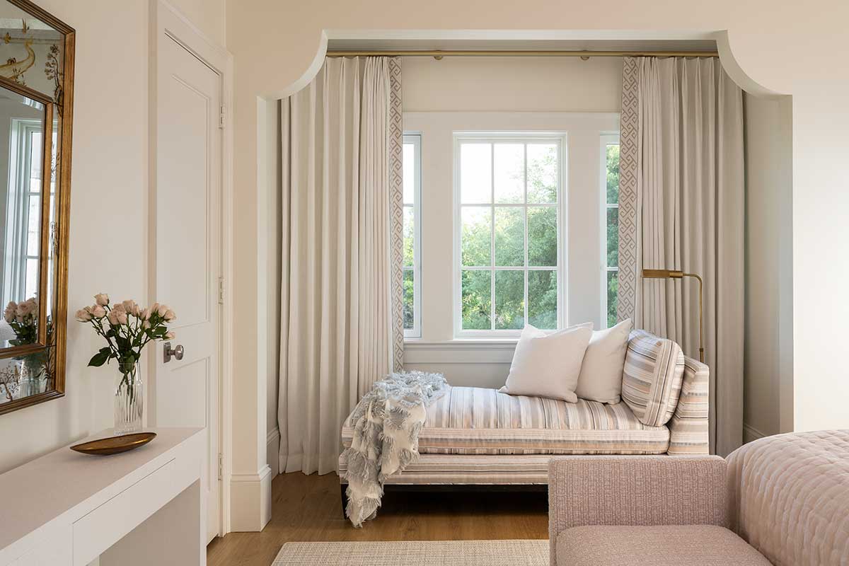 A daybed in a traditional bedroom beneath Marvin Ultimate Casement Picture windows.