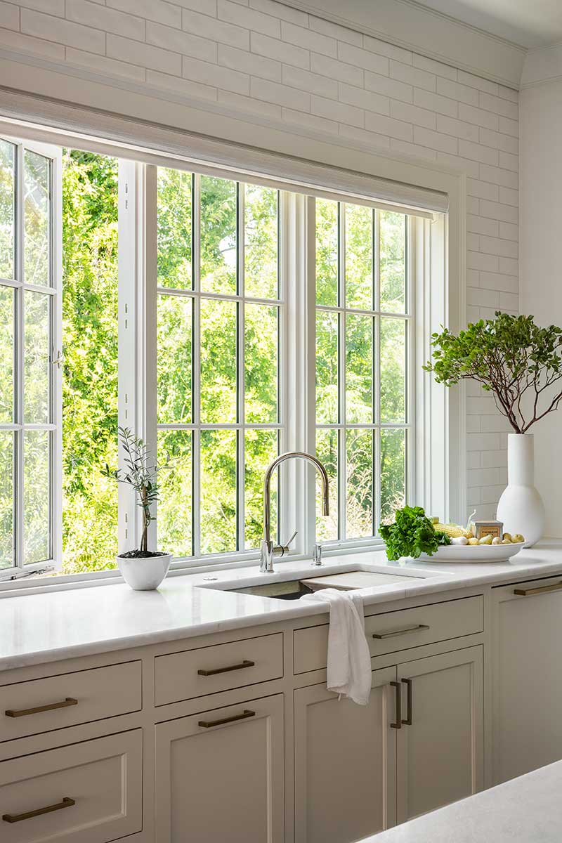 A traditional kitchen, featuring large Marvin Ultimate Casement Push-Out windows above a sink on a large countertop.