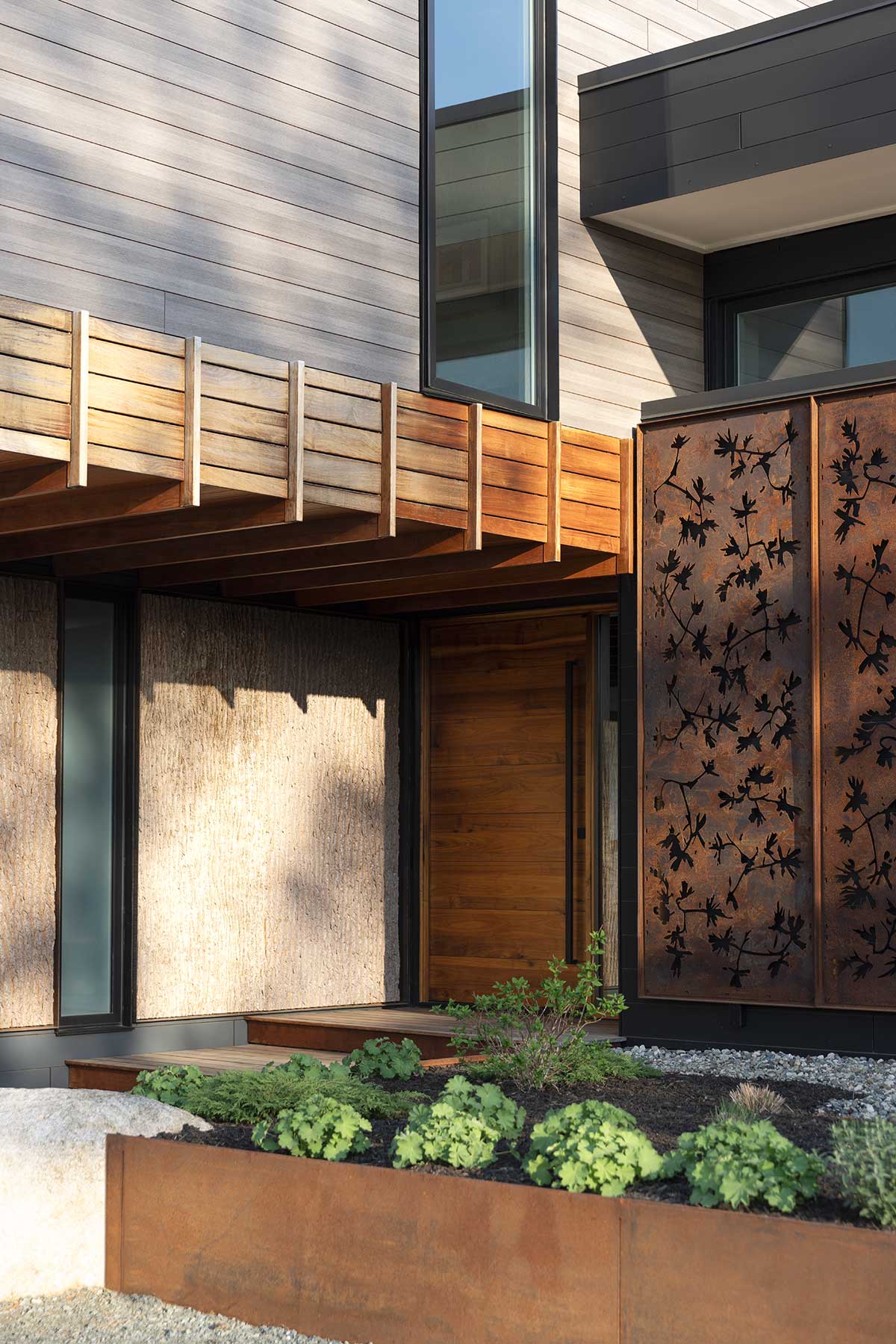 The side of a modern home in New Hampshire, with several different building materials, featuring Marvin Modern windows and doors.