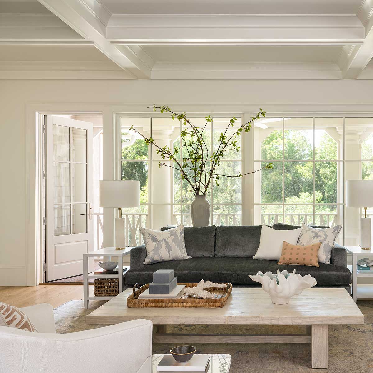 A sitting room with dark couch and light coffee table, in front of Marvin Ultimate Casement Picture windows and an Ultimate Outswing French door.