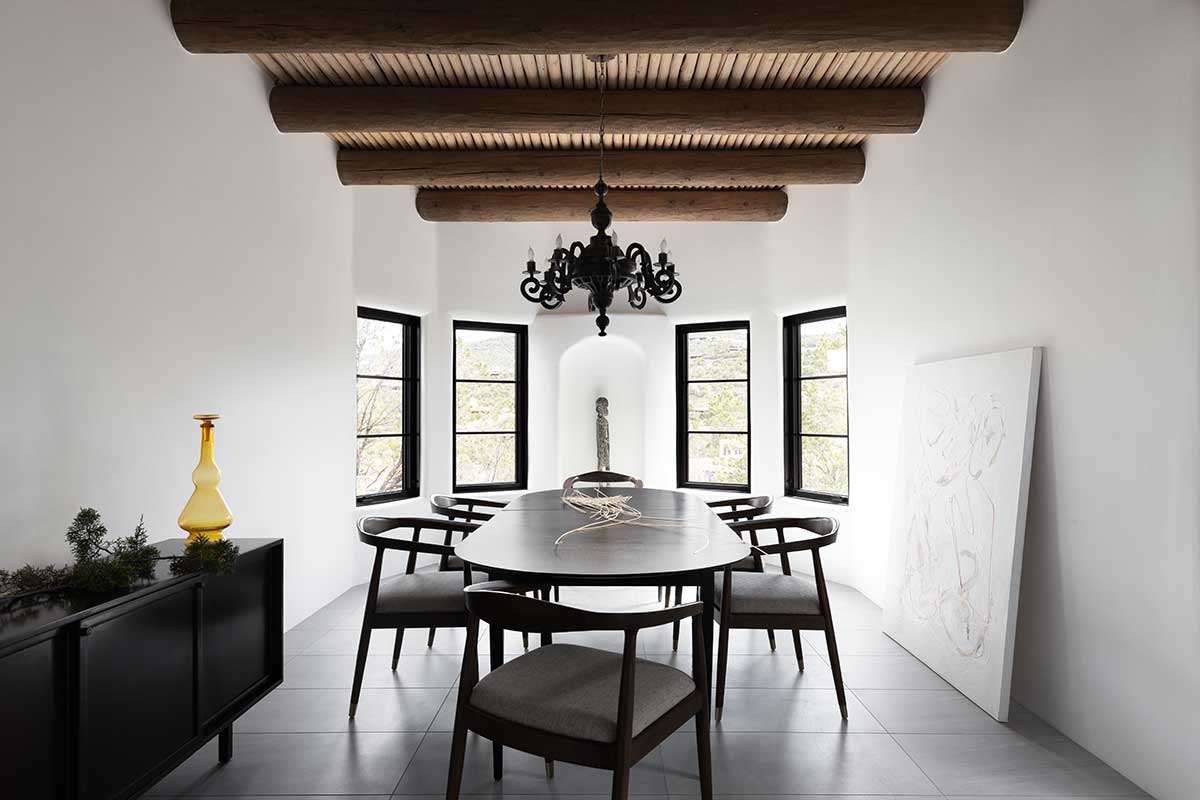 A dining room in an Adobe-style home in Santa Fe, New Mexico, with Marvin Ultimate Casement Narrow Frame windows looking out to the desert landscape.