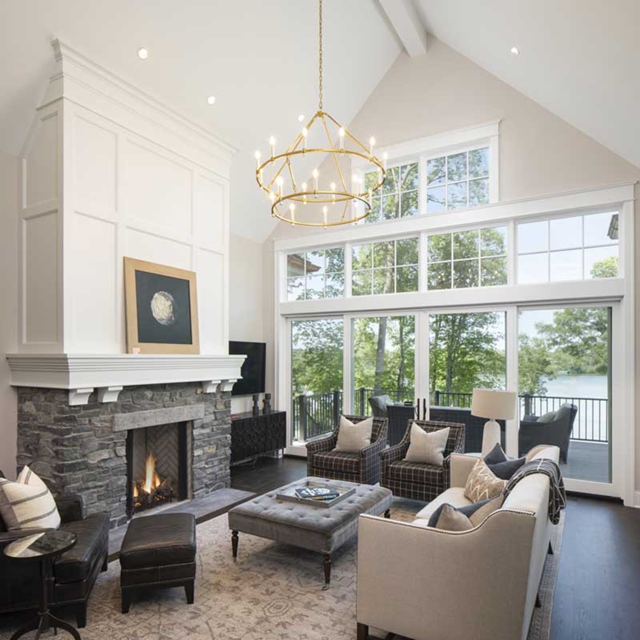 Living room with fireplace and vaulted ceilings with a lake view through sliding french doors