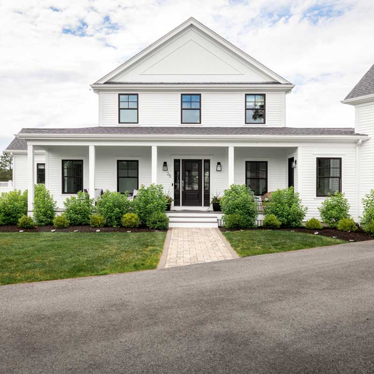 White modern farmhouse entry with front porch and black elevate double hung windows