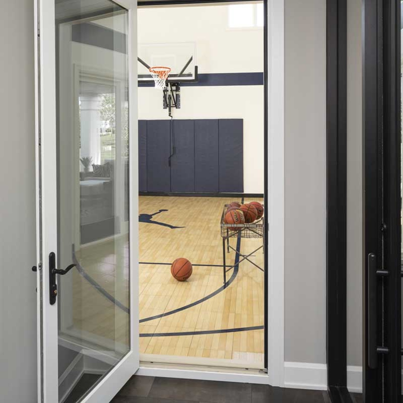 View through a swinging patio door into a home gym basketball court