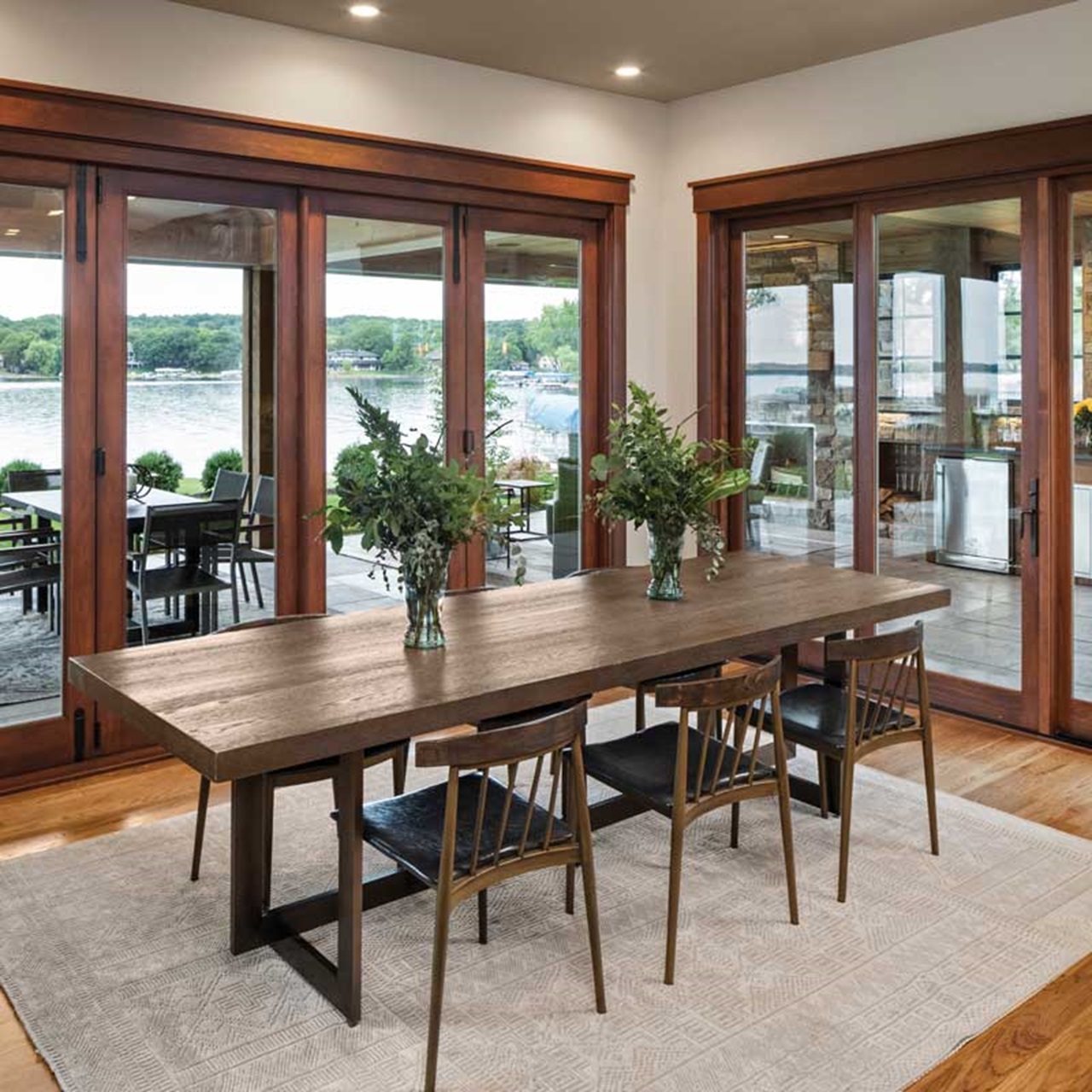 Dining room with wood table and chairs looking out to a lake through wood sliding patio door