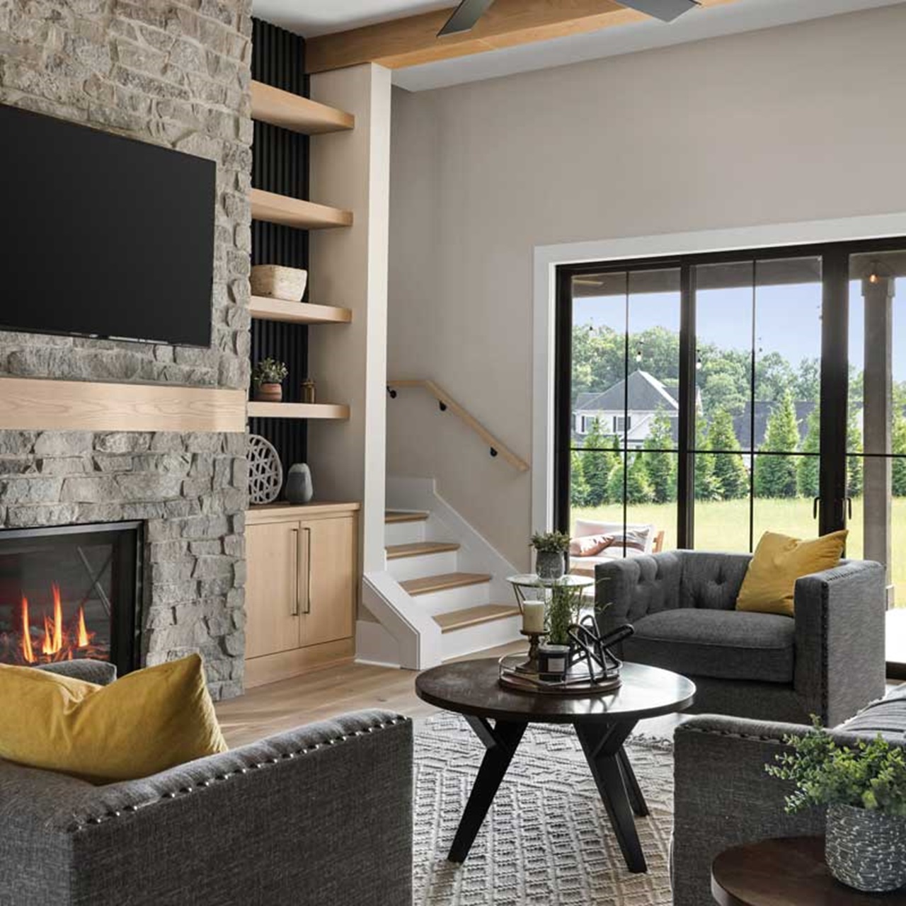 Living room with stone fireplace with seating and view out black sliding patio doors